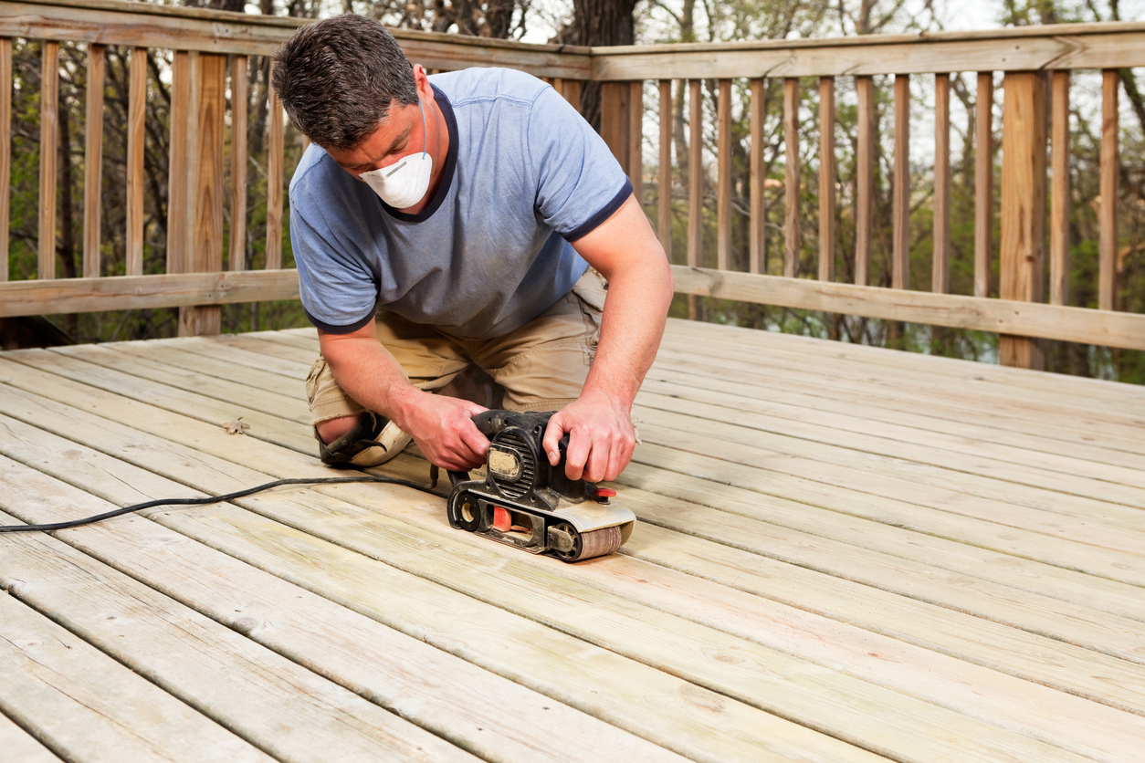 Sanding wood deck planks: a glimpse into the maintenance demands of traditional wood decking.